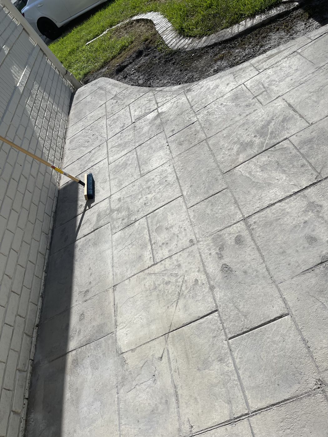 D&D Rustics stamped concrete walkway with a stone-pattern finish beside a brick home